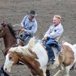 Riders pull up alongside Clay Jorgeson to help him dismount after his bareback ride at the rodeo.