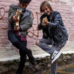 Noah Wossene, left, and Rowan Gano aim their guitars at the camera.