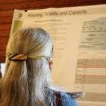 A resident reads a posterboard detailing island housing capacity at a public information and comment session in Island Center.