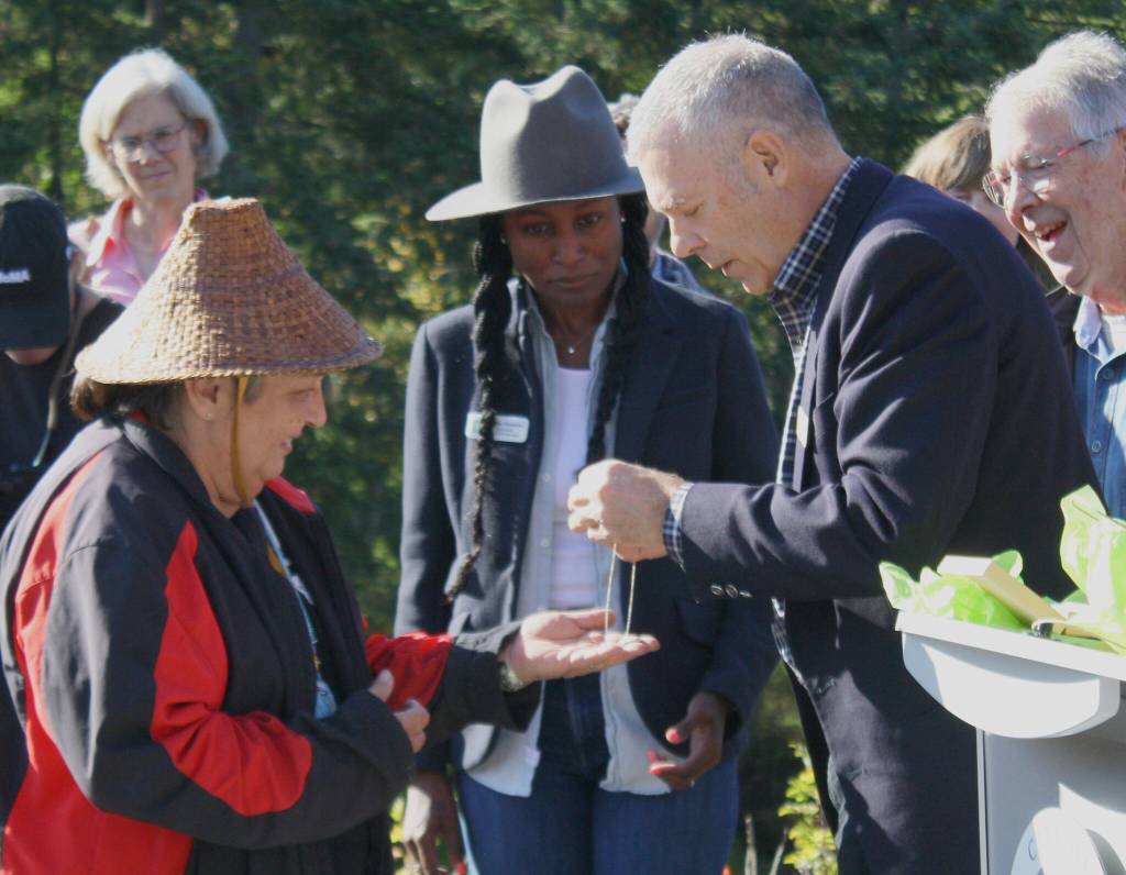 Bainbridge Mayor Joe Deets offers a gift to carver Randi Purser during the welcome pole dedication.