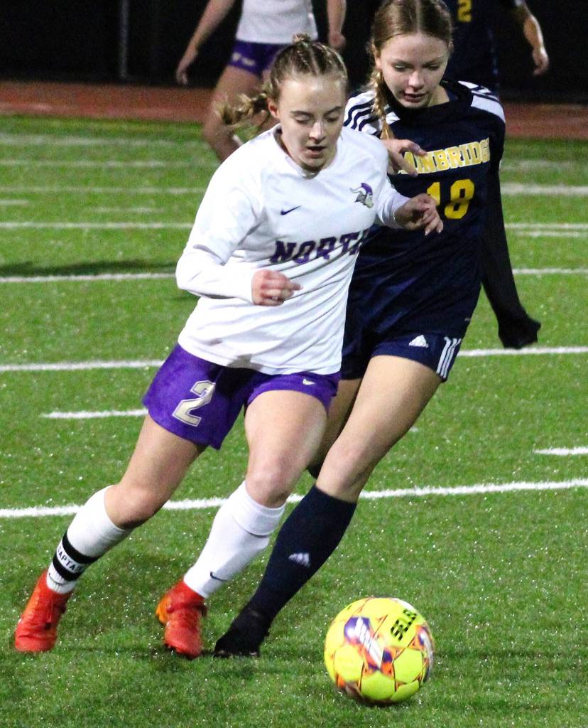 NK senior Ellie Stanford tries to keep possession of the ball against pursuing Spartan freshman Eliza Jurcak.