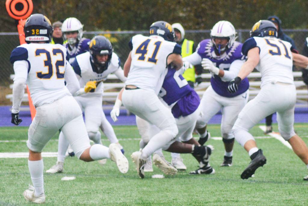 Sophomore Zach Ausmeier (41) tackles Shia Webster of Anacortes while Carson Williams (32) and Wyndham Kochenash (51) move in to help.