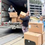 Volunteers with the nonprofit take donated boxes of toys out of a moving truck and move them inside a hospital to be given out to children.