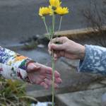 A ceremony attendee accepts a flower to place at the pole.