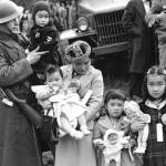 Sound Publishing file photo
Cpl. George Bushy, left, a member of the military guard which supervised the departure of 237 Japanese people for California, holds the youngest child of Shigeho Kitamoto, center, as she and her children are evacuated from Bainbridge Island on March 30, 1942.