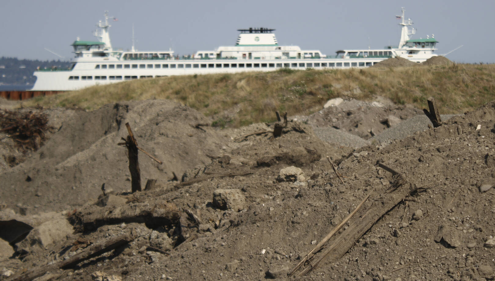 File photo
A few large piles of creosote-contaminated dirt frame the future view from Pritchard Park, while a ferry arrives in Bainbridge.