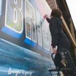 Brahmer puts the finishing touches on the mural after it is suspended on the wall.