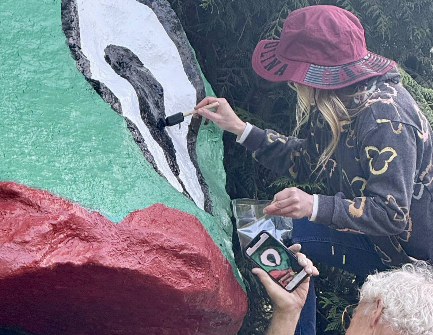 Denise Stoughton assists in repainting Frog Rock to its original visage  droopy pupil and all.
