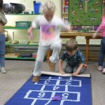 Students take turns playing hopscotch at Leaps and Bounds preschool.