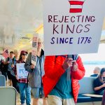 Passengers march through the passenger cabin displaying homemade signs.