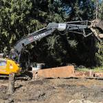 Molly Hetherwick/Kitsap News Group photos
An excavator wields a large boulder while digging up the roadway at the project site.